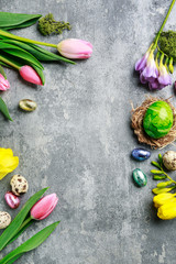 Colorful flowers and painted Easter eggs on grey, stone background