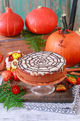 Halloween chocolate spider web cake and pumpkins around.