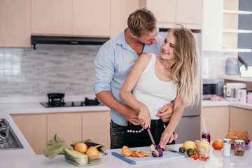 Romantic couple hugging and smiling while standing in the kitchen during cooking