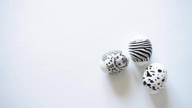 The black and white boiled chicken decorated Easter eggs with an animal print spinning on a white isolated background, copy space