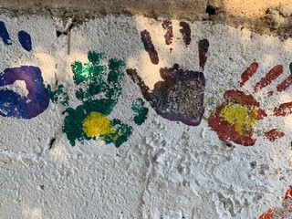 Mural de manos con pintura de colores y caritas felices