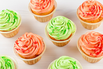 Tasty colorful cupcakes closeup on white wooden background, top view