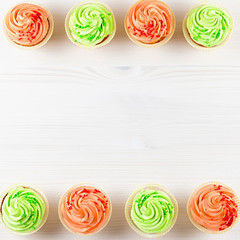 Tasty colorful cupcakes closeup on white wooden background, top view