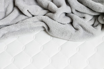 Grey blanket with pompoms on the new mattress. - obrazy, fototapety, plakaty