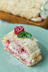 Meringue cake roll slice on a plate with berries, on a gray background