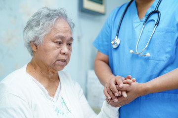 Asian nurse physiotherapist doctor care, help and support senior or elderly old lady woman patient lie down in bed at hospital ward : healthy strong medical concept.
