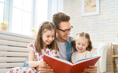 Obraz premium father reading a book to his daughters