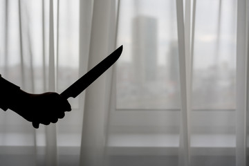 silhouette of a man's hand with a knife, transparent white curtain background