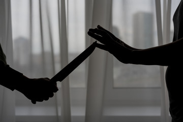 female hands with open palms stop an aggressive man with a knife in his hands