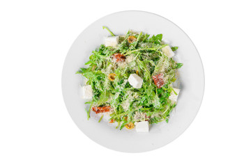 Salad with with arugula, feta, dried tomatoes, olives and grated cheese on plate, white isolated background, view from above