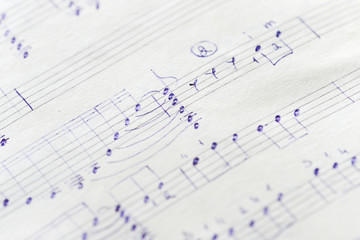 Fragment of an old musical notebook with hand written notes close up