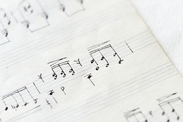 Fragment of an old musical notebook with hand written notes close up