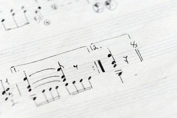 Fragment of an old musical notebook with hand written notes close up