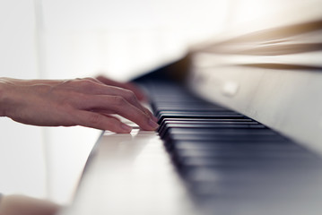Close up view of woman hands playing electronic piano at home. Seen from side view while she pressing piano keys by both hands. She practicing music skill. Hobby and activity at home concept.