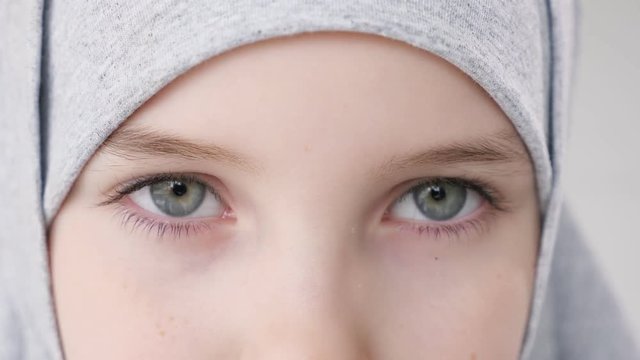 Closeup eyes of muslim arabian 9 years teen girl in grey hijab looking at camera.