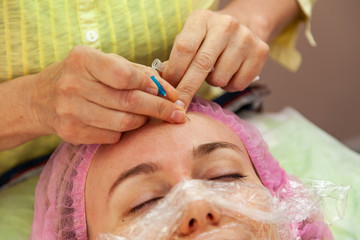 A young girl is lying on a couch during cosmetic procedures with a mask on the face above which...