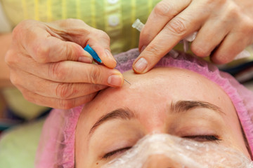 A young girl is lying on a couch during cosmetic procedures with a mask on the face above which...