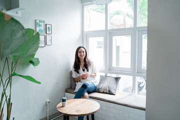 smiling asian woman with a glass of juice sitting