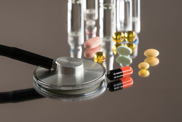 medical stethoscope with pills and ampoules on a mirror background with reflection