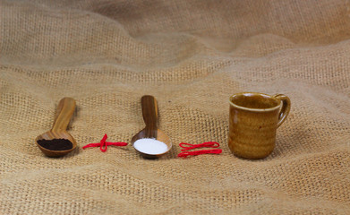 cup of coffee next to wooden spoons with coffee and sugar
