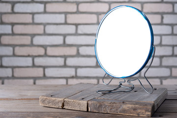 Desktop mirror on the table with a brick background