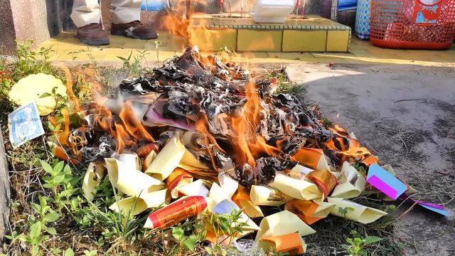 Chinese burning offerings of hell money to ancestor during Qingming