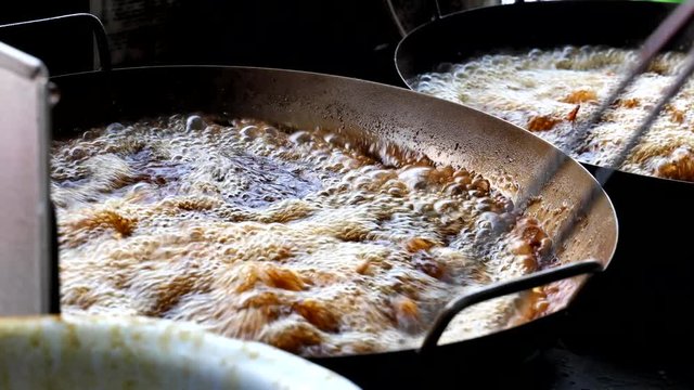 Person deep frying chicken wings in wok with cooking oil
