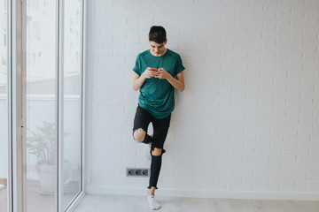 student or young teenager with mobile phone on the wall supported