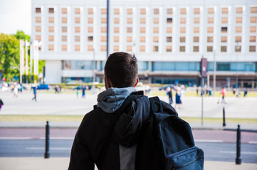 Tourist with backpack from the back, rear. Traveller among the city, with walking blurred people in the background