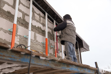 Fototapeta premium A worker installs a metal profile on the walls of a siding house