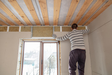 Fototapeta premium Worker installs drywall on the walls in the room
