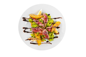Salad with roast beef with fried potatoes, eggs, lettuce, tomatoes balsamic vinegar, sauce on plate, white isolated background, view from above