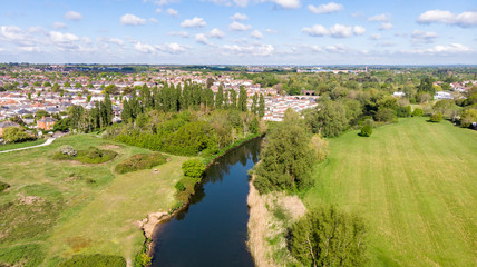 An aerial view of an urban area along a park and river under a majestic blue sky and white clouds