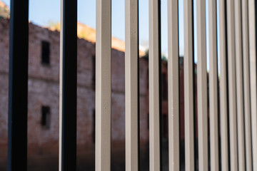 cast iron fence bars close-up with blurred brick background