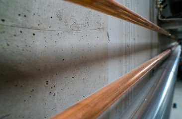 long new shiny copper pipes leading along a concrete cellar wall