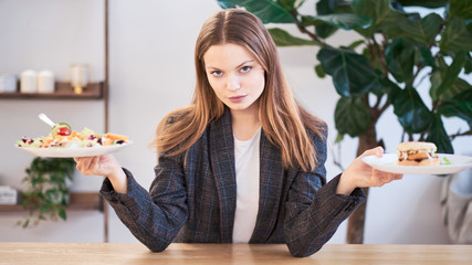 Pensive woman making decision between healthy food and fast food. healthy eating concept. business woman in a jacket having lunch at the office