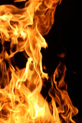 Fototapeta premium Closeup of a large fire. Wooden planks to the fire. The fire is lit in the night.