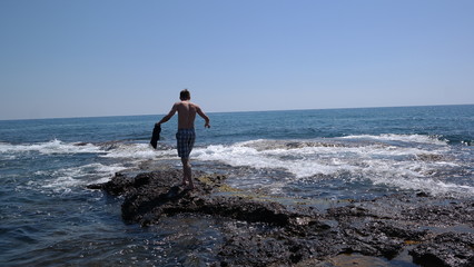 Young man walking on the shore near the sea