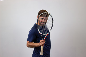Portrait of handsome young man playing tennis holding a racket with brown hair and a funny...