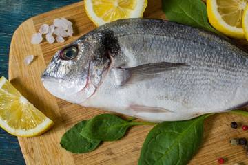 Raw fresh dorado fish on a cutting board with lemon and spices. View from above.