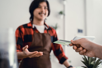 close up of man's hand worker in cafe counter receiving payment via credit card from customer