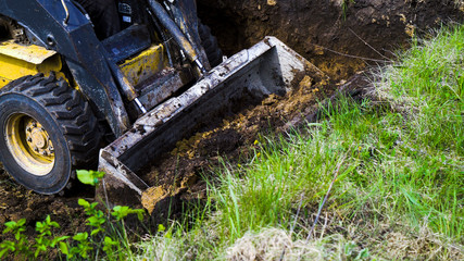 partial view of dirty mini loader digging pit during earth works