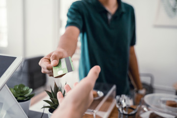 male customers pay their purchases to the cashier using a credit card