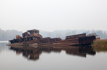 Old sunken ship in water in a foggy day