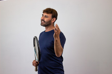 Portrait of handsome young man playing tennis holding a racket with brown hair in harmony, facing...