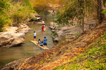 Group of tourist visiting and sitting on the bamboo raft floating  rafting and rowing on the rapids. located in Mae Wang National Park in Chiang MaiThailand