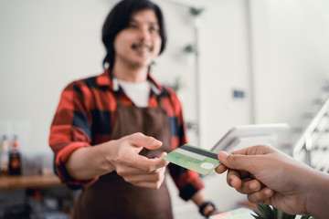 man worker in cafe counter receiving payment via credit card from customer