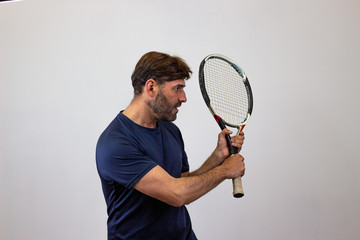 Portrait of handsome young man playing tennis holding a racket with brown hair looking strong,...