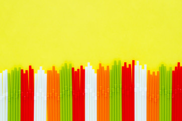 Colorful plastic straws on yellow background for summer season concept.