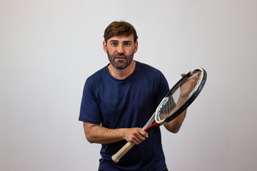 Portrait of handsome young man playing tennis holding a racket with brown hair motivated, looking...